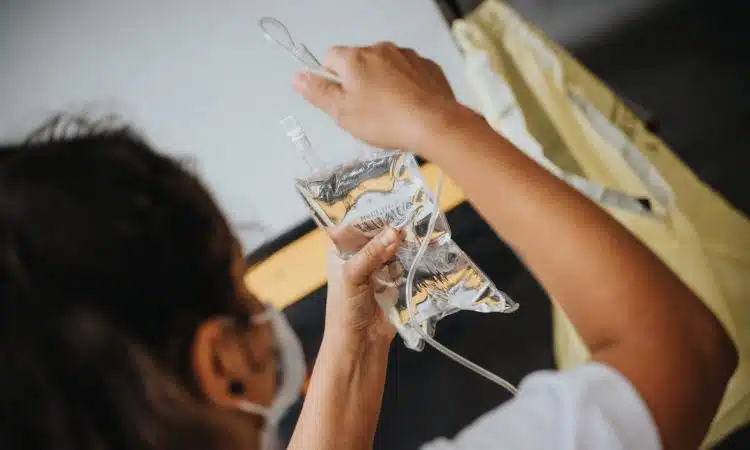 woman in white shirt holding clear plastic cup